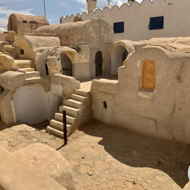 Cour intérieure de Ksar Haddada avec ghorfas voûtées et escaliers typiques de l'architecture berbère tunisienne.